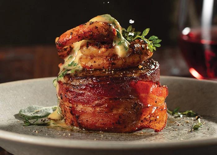 Bacon-wrapped filet mignon with grilled shrimp and seasoning on a dinner plate