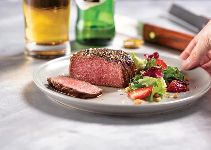 Grilled, seasoned filet mignon with side salad with strawberries.