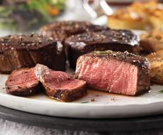 Seasoned sliced steaks on a white platter