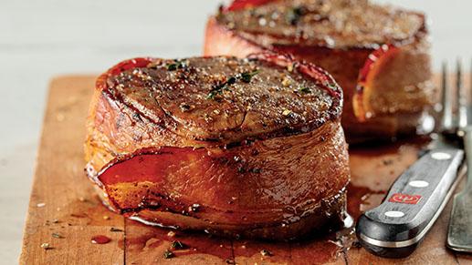 bacon-wrapped filet mignons on a cutting board