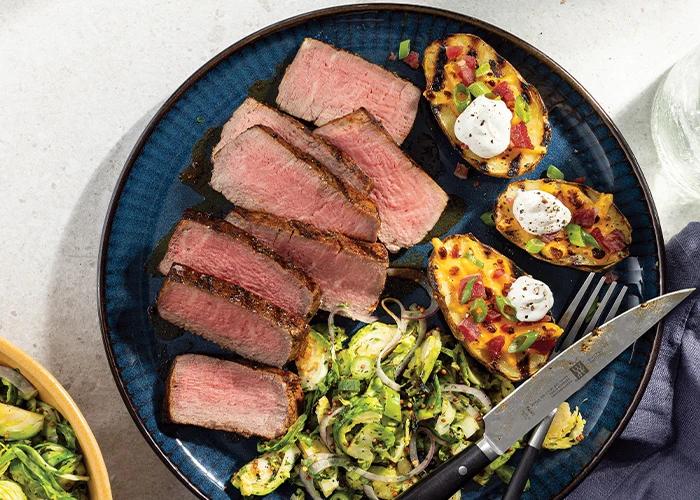 Seasoned and sliced grilled steak garnished with tomatoes and onions.